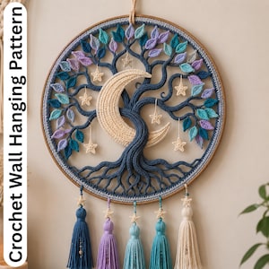 Può includere: Un arazzo da parete all'uncinetto fatto a mano con un design ad albero, una luna crescente e stelle. L'albero ha rami blu, foglie colorate e stelle color crema. Il pezzo è incorniciato in un cerchio di legno e ha nappe pendenti.