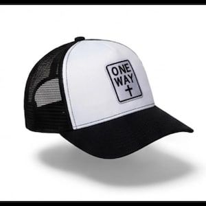 Peut inclure: Une casquette trucker noire et blanche avec un panneau avant blanc portant un écusson rectangulaire affichant le texte ONE WAY et un symbole de croix. La casquette possède une visière noire et des panneaux latéraux et arrière en maille noire.