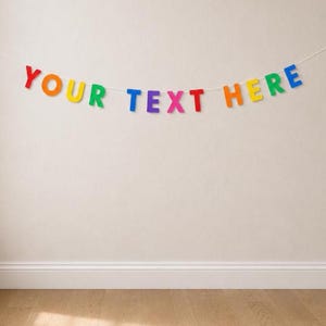 May include: A decorative banner featuring individual, multi-colored letters strung together on a white cord. The letters spell out the phrase YOUR TEXT HERE in a variety of bright colors including red, orange, yellow, green, blue, and pink.