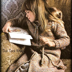 May include: A young girl wearing a brown and beige knitted hooded cardigan with a zipper and a tie belt. She is sitting on a couch and reading a book. The book has a brown cover with a white illustration. The text "Tick Tock Knits" is visible in the lower left corner of the image.