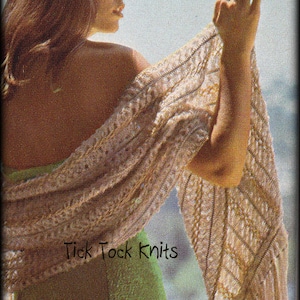 Puede incluir: Una mujer lleva una larga estola de ganchillo con un patrón de color marrón claro y blanco. La estola tiene flecos a lo largo del borde inferior. La mujer lleva un vestido verde y tiene el pelo largo y castaño. El texto "Tick Tock Knits" es visible en la imagen.