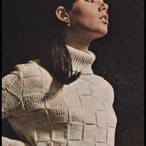 May include: A white knitted sweater and skirt set with a checkered pattern. The sweater has a turtleneck and the skirt has a chain belt.