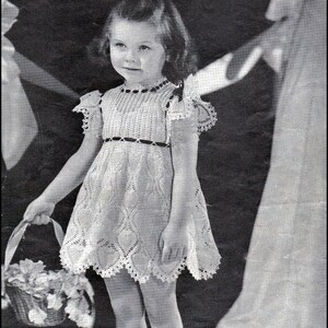 May include: A young girl in a white crocheted dress holds a basket of flowers. She is wearing white socks and black shoes. The background is a blurry image of a woman in a white dress.
