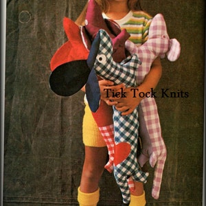 May include: A young girl holds four plush dachshund toys. The toys are made of different fabrics and have gingham patterns. The girl is wearing a yellow and green striped shirt and yellow shorts. The text "Tick Tock Knits" is visible in the image.