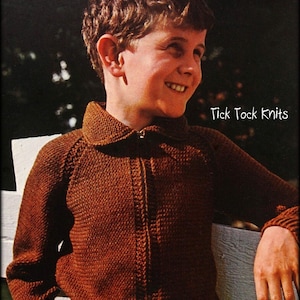 May include: A brown knitted zip-up sweater with a collared neckline. The sweater is worn by a young boy standing in front of a white fence. The text "Tick Tock Knits" is visible in the upper right corner of the image.