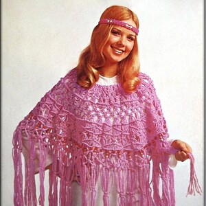 Puede incluir: Un poncho de crochet rosa con flecos. El poncho tiene un delicado patrón de calado y lo lleva una mujer con el pelo largo y rubio y una diadema.