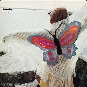 May include: A white crocheted shawl with a large butterfly design in shades of blue, pink, and orange. The butterfly has a black body and is attached to the shawl. The shawl has fringe around the edges. "Tick Tock Knits" is printed at the bottom of the image.