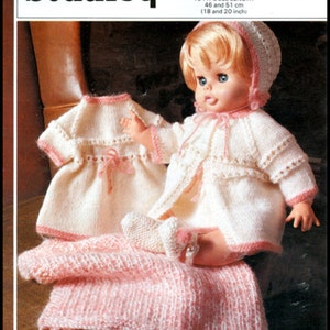 Può includere: Uno schema di maglia per un abito da bambola, che comprende un vestito bianco, un cardigan bianco con bordi rosa, un berretto rosa e una coperta rosa. Lo schema è per una bambola alta 46 o 51 cm.