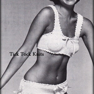 Op de afbeelding: Een wit gecrochet bikini top en broekje met een strikdetail. De bikini wordt getoond op een model met kort donker haar.
