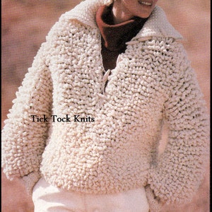 May include: A white crocheted sweater with a textured, puffy design. The sweater has a V-neck and long sleeves. The model is wearing a white crocheted hat and white pants. The text "Tick Tock Knits" is visible on the sweater.