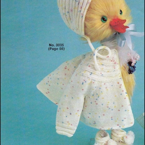 May include: A knitted doll with a white hat and a white sweater with colorful specks. The doll has a yellow fluffy body and a red beak. The doll is wearing white booties with pom-poms. The doll is on a blue background. No. 3035 (Page 56) TICK TOCK KNITS