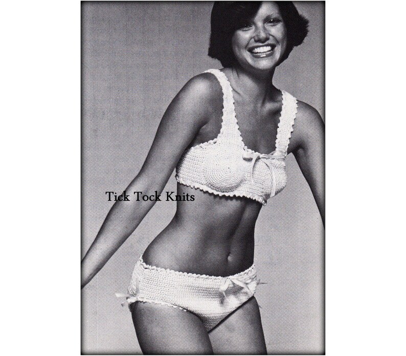 Op de afbeelding: Een wit gehaakt bikini-topje en -broekje met een strikdetail. De bikini wordt getoond op een model met kort donker haar. De tekst "Tick Tock Knits" is op de afbeelding gedrukt.