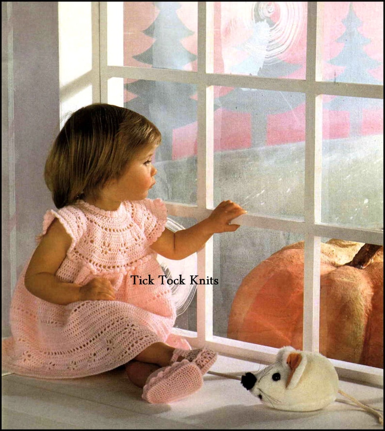May include: A little girl in a pink crocheted dress sits by a window looking out at a pumpkin and a white mouse. The window is decorated with a winter scene. The text "Tick Tock Knits" is visible in the image.