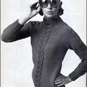 May include: A black turtleneck sweater with a thick cable knit design. The sweater has a relaxed fit and long sleeves. The model is wearing the sweater with a pair of sunglasses.