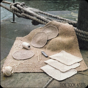 Può includere: Una collezione di articoli all'uncinetto, tra cui un grande tappeto, diversi sottopiatti rotondi e sottobicchieri quadrati. Gli articoli sono realizzati con fibre naturali e sono esposti su una superficie in pietra. La lana e gli aghi da maglia sono anche visibili nell'immagine.  TICK TOCK KNITS è stampato nella parte inferiore dell'immagine.