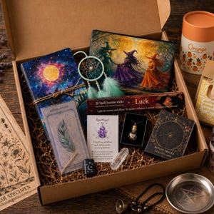 May include: A cardboard gift box containing a celestial-themed notebook, a small dreamcatcher, a pouch with a witch illustration, a box of Luck incense sticks, a Witchy Oracle card deck, a small crystal vial necklace, a crystal, and bath salts.