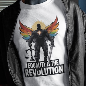 May include: White t-shirt featuring a muscular figure with rainbow wings, holding a sword and scales. The text "EQUALITY IS THE REVOLUTION" is printed below the figure in a bold, black font. The shirt is worn under a black leather jacket.