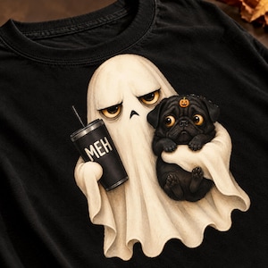 Puede incluir: Una camiseta negra con una ilustración detallada de un fantasma color crema con expresión aburrida que sostiene un vaso negro con el texto MEH y un cachorro de pug negro con un pequeño icono de calabaza naranja en la frente.