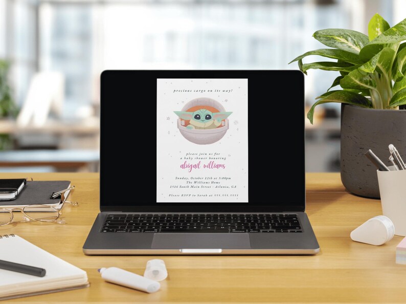 May include: A laptop displays a baby shower invitation featuring a cartoon character in a pod. The invitation text reads "precious cargo on the way!" and includes details for a baby shower honoring Abigail Williams.