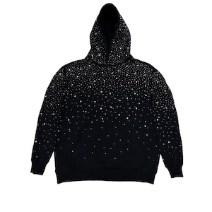 Pode incluir: Moletom preto com capuz e padrão de pontos brancos que se desvanece de cima para baixo. O moletom tem um bolso frontal e punhos e bainha canelados. O capuz está levantado e a roupa está isolada em um fundo branco.
