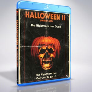 Könnte beinhalten: Eine blaue Blu-ray-Hülle für Halloween II Grindhouse Edition. Das Cover zeigt einen schwarzen Hintergrund mit einer zentralen orangefarbenen Kürbis-Totenkopf-Grafik, dem Titel und den Sätzen The Nightmare Isn't Over! und The Nightmare Has Only Just Begun...!