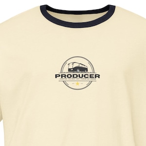 May include: Cream-coloured ringer t-shirt with navy blue trim on the collar and sleeves. The shirt features a circular logo with the word "PRODUCER" and an illustration of a vehicle. A casual, everyday wear tee.