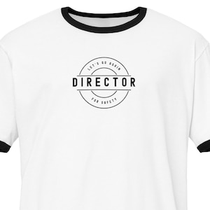 May include: White ringer t-shirt with black trim on the collar and sleeves. The shirt has a circular graphic in the centre with the words "DIRECTOR" and "LET'S GO AGAIN FOR SAFETY" in black text.