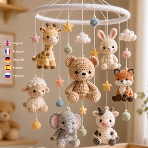 Pu&ograve; includere: Una giostrina per culla all'uncinetto con un orsetto beige centrale circondato da una giraffa, una pecora, un elefante, una mucca, un coniglio e una volpe. Gli animali sono appesi a un telaio circolare bianco con stelle, nuvole e sfere.