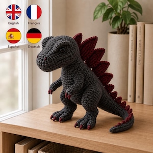 Op de afbeelding: Een donkergrijs gehaakt dinosaurus knuffeldier met een rij donkerrode stekels langs de rug en staart, en bijpassende rode klauwen aan de voeten en handen. Het wezen heeft een getextureerd garen oppervlak, een opvallende snuit en donkere ogen.