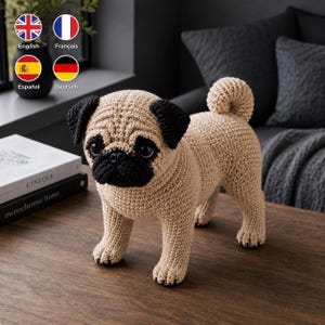 May include: A crocheted pug figurine featuring a tan body with black ears, a black muzzle, and black paws. The dog has a curled tail and dark, round eyes, crafted with a visible yarn texture throughout the entire structure of the animal.