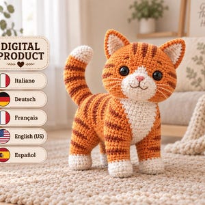 Könnte beinhalten: Ein gehäkeltes Katzenspielzeug mit orangefarbenen und dunkelbraunen Tigerstreifen, weißer Brust, weißen Pfoten und einer weißen Schwanzspitze. Die Katze hat große schwarze Sicherheitsaugen, eine rosa gestickte Nase und weiße Schnurrhaare. Ein digitales Produktlabel ist links.