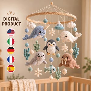 Puede incluir: Un móvil de ganchillo para bebé con un marco circular de madera y figuras de peluche colgantes que incluyen un narval azul, una ballena blanca, un pingüino, una foca gris y una morsa marrón, con pequeñas nubes, copos de nieve y algas tejidas.
