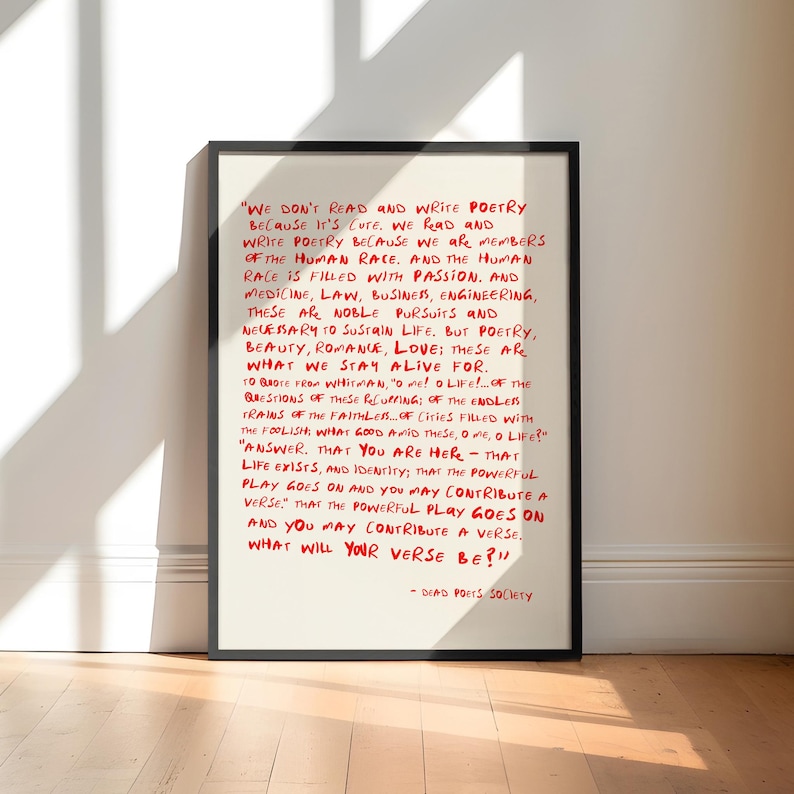 May include: A framed wall art print featuring a cream-colored background with handwritten-style red text. The quote reads: "We don't read and write poetry because it's cute. We read and write poetry because we are members of the human race."