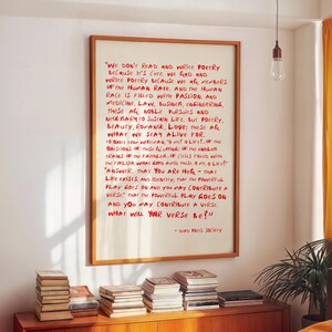 May include: A framed wall art print featuring red handwritten-style text on a cream background. The text includes a quote from Dead Poets Society: We don't read and write poetry because it's cute. We read and write poetry because we are members of the human race.
