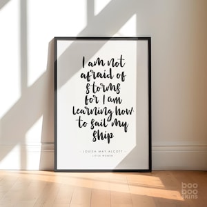 May include: Black and white typography print with the quote "I am not afraid of storms for I am learning how to sail my ship" by Louisa May Alcott, author of Little Women.