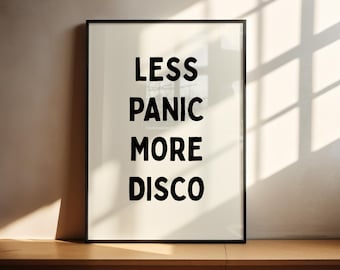 May include: A black framed poster with white background and the text "Less Panic More Disco" in black bold letters.