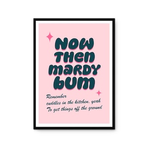 May include: A framed pink art print with the words "NOW THEN MARDY BUM" in teal bubble letters. The print also includes the text "Remember cuddles in the kitchen, yeah To get things off the ground" in a smaller font.