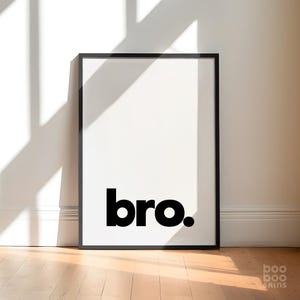 Peut inclure: Une affiche encadrée noire avec le mot "bro." imprimé en lettres noires et grasses sur fond blanc.