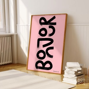 May include: A pink poster with the word "Relax" written in black, stylised lettering. The poster is framed in a light wood frame.