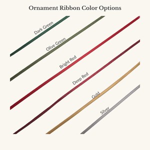 May include: A color chart titled Ornament Ribbon Color Options displaying six diagonal ribbon samples in dark green, olive green, bright red, deep red, gold, and silver. Each ribbon is labeled with its corresponding color name in black text.