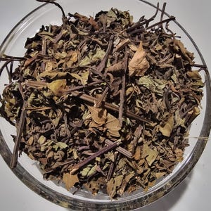 A glass bowl filled with dried herbs and leaves, creating a visually appealing and natural arrangement.