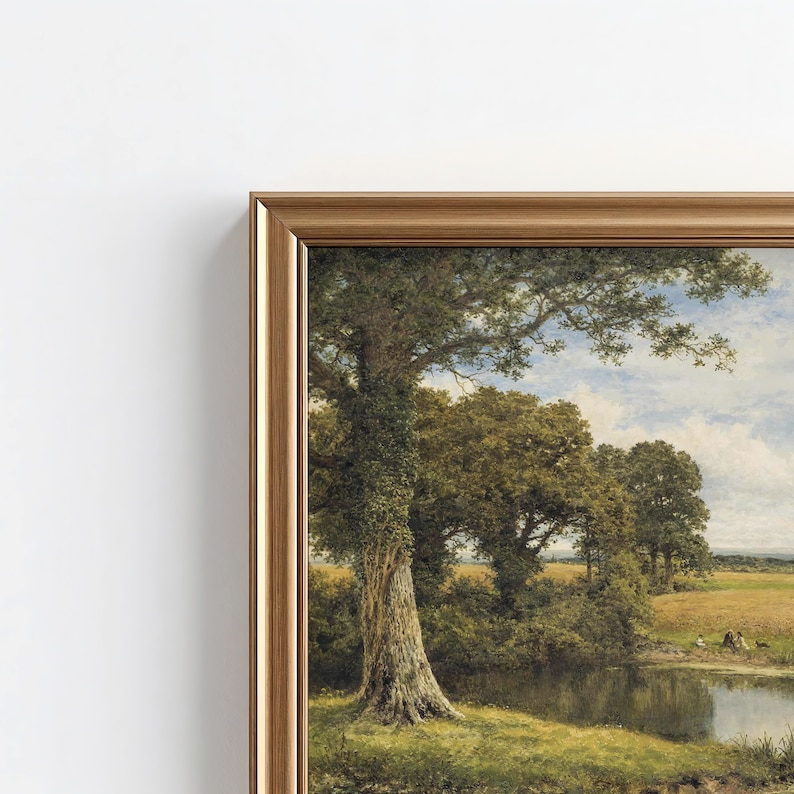 May include: A framed landscape painting featuring a large, textured tree trunk in the foreground next to a calm pond. The scene includes lush green trees, a golden field, and a cloudy blue sky, all enclosed within a metallic gold-toned frame.