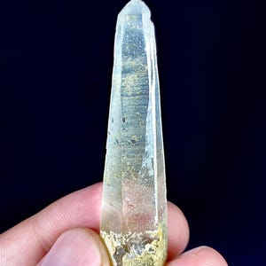 以下が含まれることがあります： 先端が尖った透明で細長い水晶のポイント。基部は質感のある淡い黄色をしています。結晶には内部にインクルージョンが見られ、全長にわたって自然なファセットがあり、光を反射する半透明の外観を呈しています。