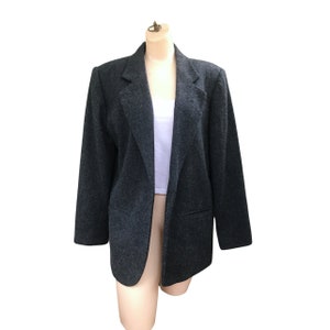May include: A dark gray blazer with a long, open front and a single pocket on the left side.