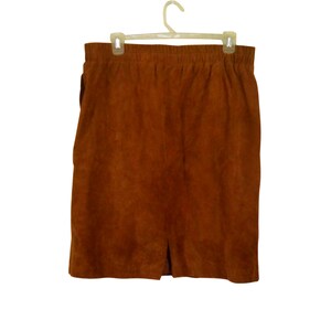 May include: A brown suede skirt with a straight silhouette and a small slit at the bottom.