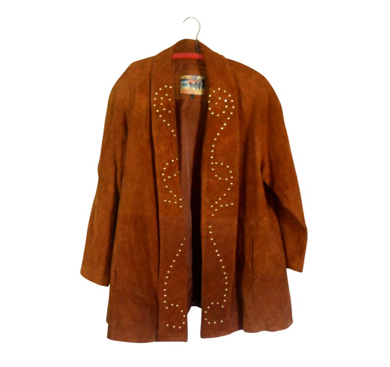 May include: A brown suede jacket with gold studs in a geometric pattern. The jacket has a shawl collar and long sleeves.