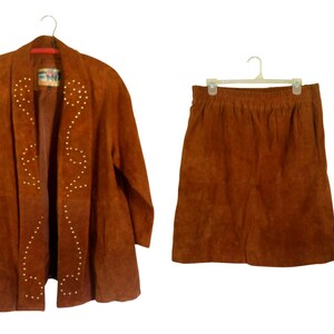 May include: A brown suede jacket and skirt set. The jacket has a shawl collar and is decorated with gold studs in a geometric pattern. The skirt is a-line and has a simple design.