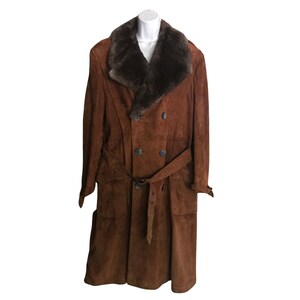 May include: A brown suede coat with a large fur collar and a belt. The coat has a double-breasted closure and two pockets.