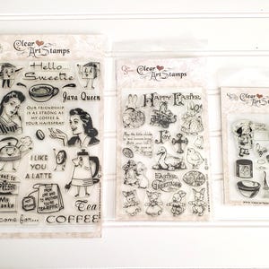 May include: Three clear art stamp sets. The first features coffee-themed illustrations and text like "Java Queen" and "Coffee-zilla." The second set has Easter-themed images. The third set includes kitchen-related illustrations.