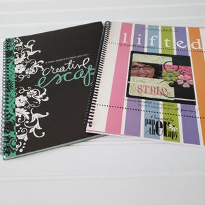 May include: Two spiral-bound books. One has a black cover with white floral designs and the words "creative escape" in teal script. The other book has a colorful striped cover with the word "lifted" and the word "style".